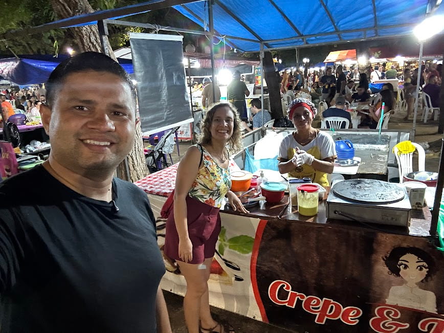 Rômullo e Ludmilla na Feira do Bosque, em Palmas, durante o primeiro dia da viagem ao Jalapão em grupo com a RF TUR, provando tapioca e crepe artesanal.